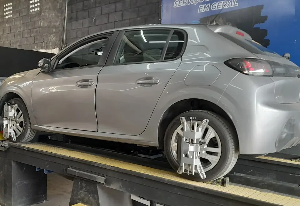 Carro cinza na bancada de alinhamento com os sensores nas rodas
